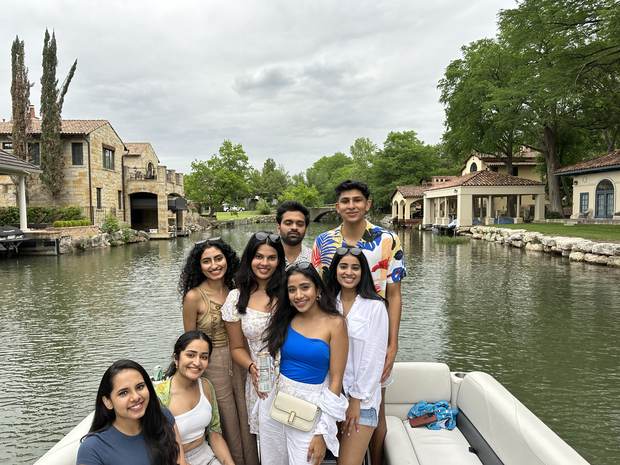 Friends posing on a LakeTime pontoon along a Lake Austin canal lined with luxury homes