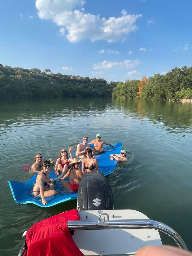 Group relaxing on the floating mat on a calm stretch of Lake Austin
