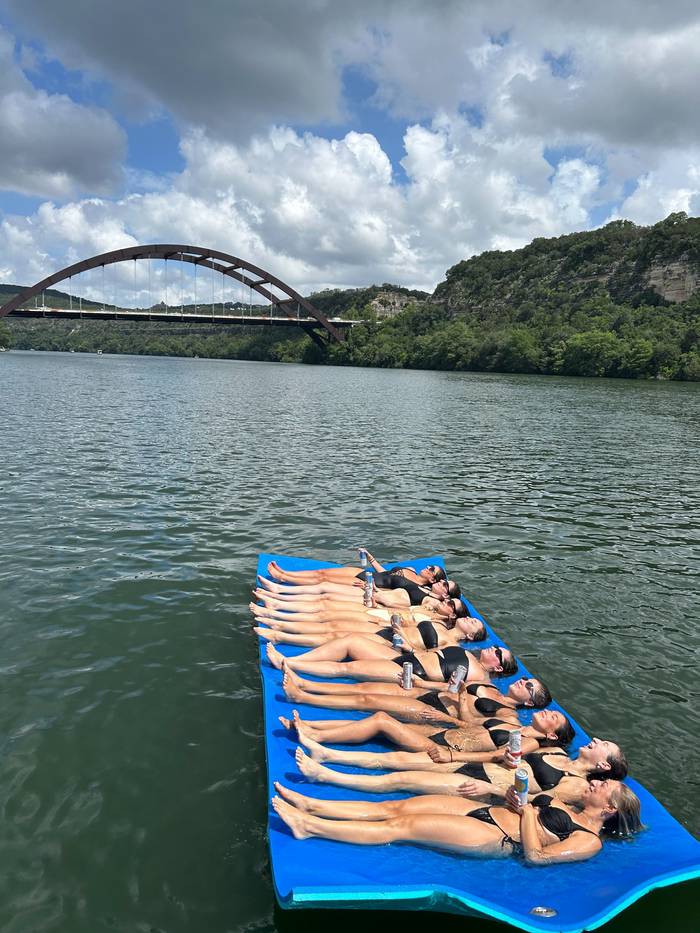 Friends relaxing together on the floating mat on Lake Austin near the 360 Bridge