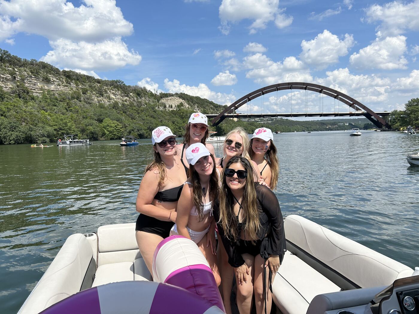 Group of friends posing on a LakeTime pontoon near the 360 Bridge