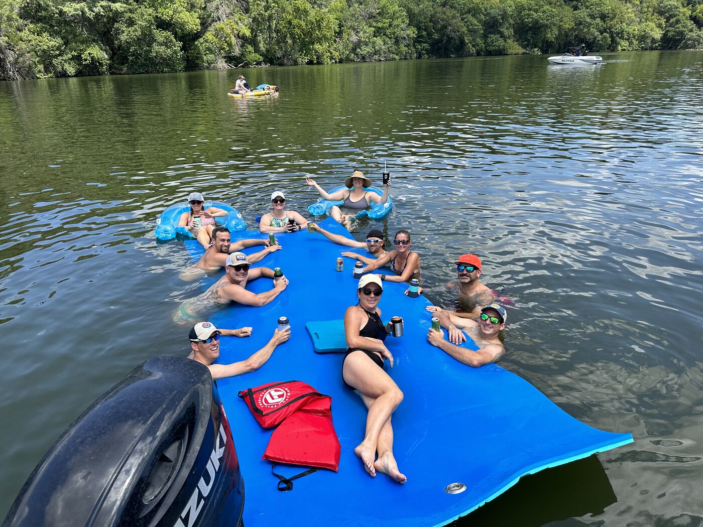 Large group toasting together on the floating mat on Lake Austin