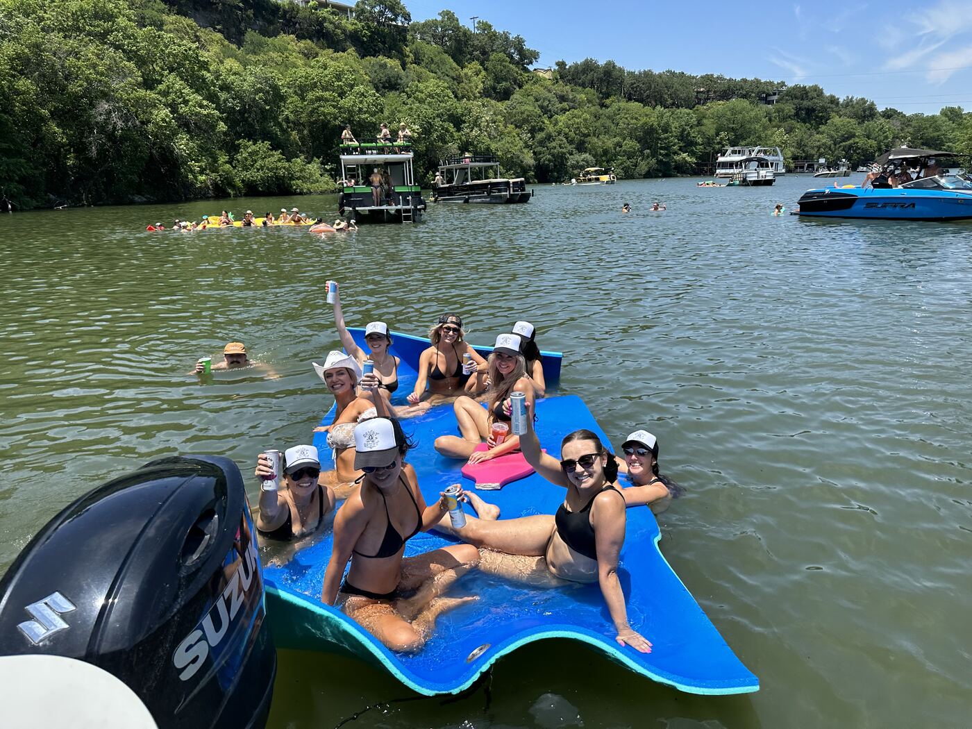 Group of friends posing aboard a LakeTime pontoon near the 360 Bridge