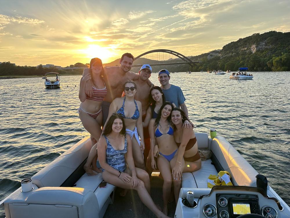 Friends celebrating a golden hour sunset cruise aboard a LakeTime pontoon on Lake Austin
